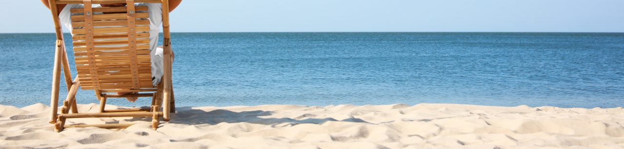 Young man relaxing in deck chair on sandy beach
