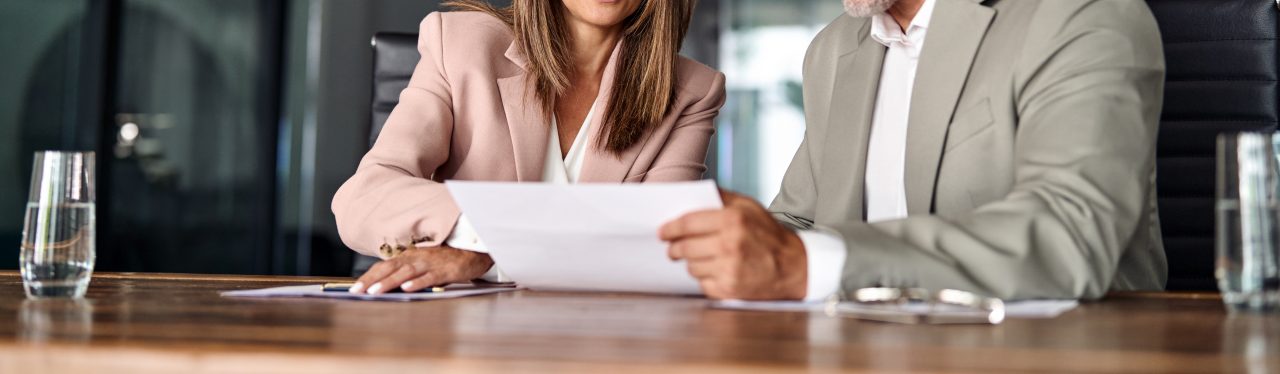 Two professional executives discussing financial accounting papers in office.